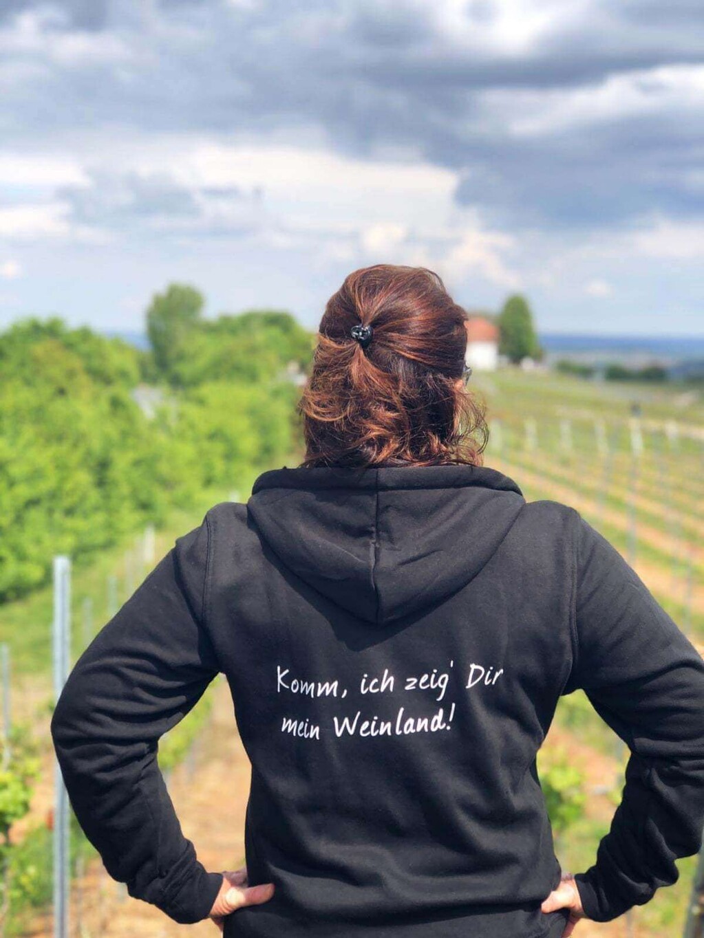 Frau von hinten mit Hoodie Komm, ich zeig Dir mein Weinland blickt auf Weinberge.